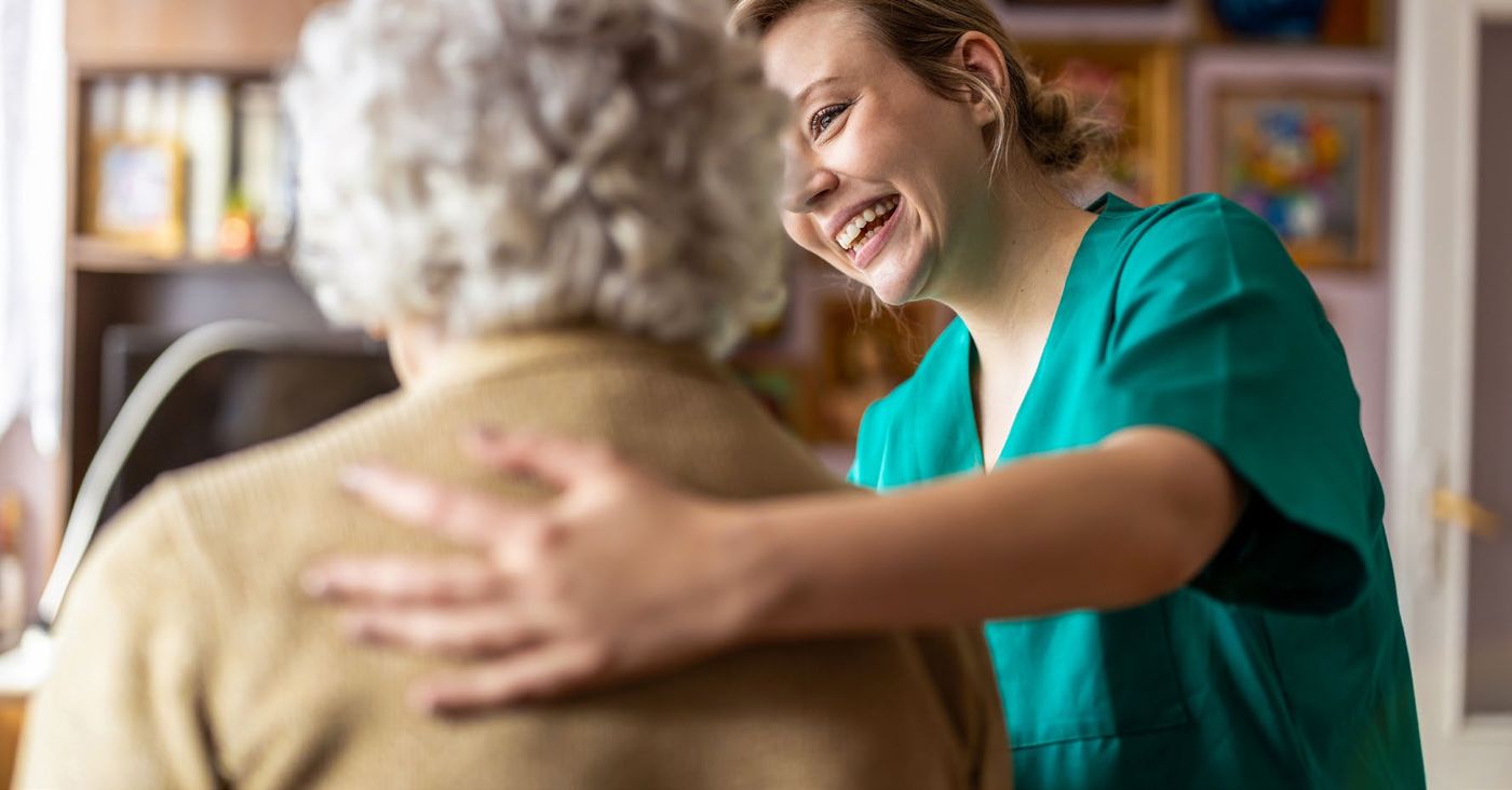 Une soignante souriante accompagne une résidente