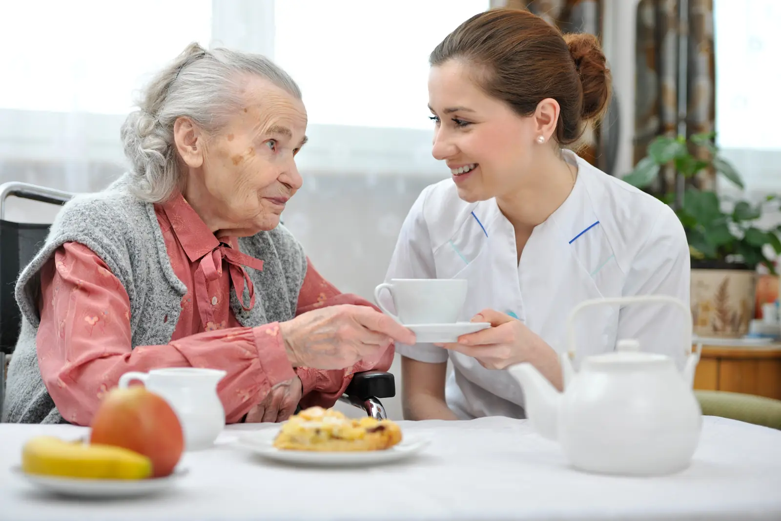 Une soignante partage un moment à table avec une résidente